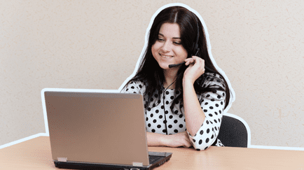 Healthcare worker sitting at a desk with a laptop, using a headset.