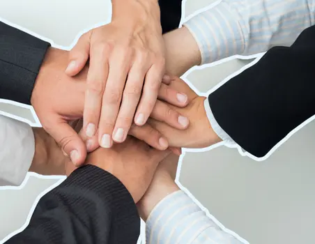 Zes handen van verschillende personen gestapeld op elkaar, als symbool voor samenwerking en diversiteit.