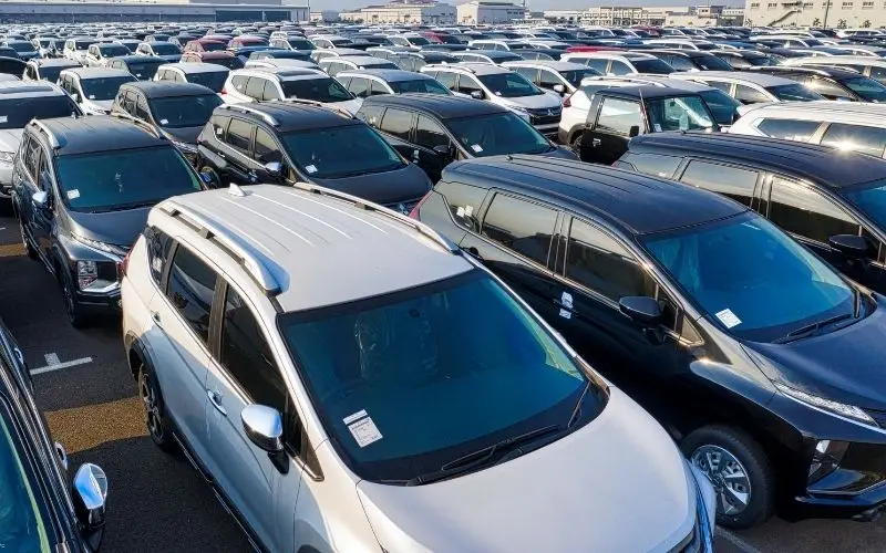 Large outdoor parking area filled with rows of parked cars arranged in long lines.